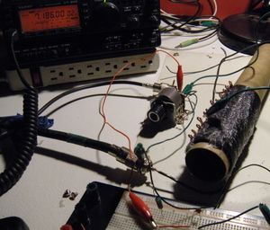 A makeshift antenna tuner on a breadboard with a variable capacitor and an inductor made from wire wrapped around a cardboard tube